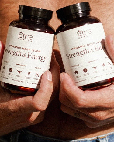Two hands holding bottles of 'Strength & Energy' supplement with visible branding.